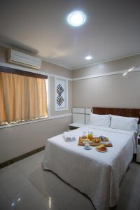 um quarto de hotel com uma cama com comida em Benvenuto Palace Hotel em Governador Valadares