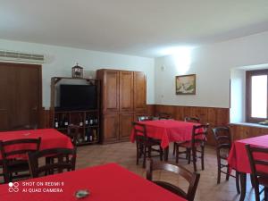 a dining room with red tables and chairs and a flat screen tv at AZIENDA AGRITURISTICA LA VECCHIA QUERCIA in Aquino