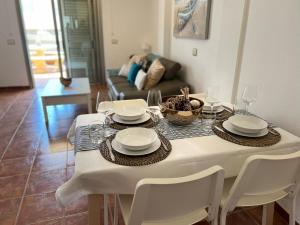 uma mesa de jantar branca com pratos e cadeiras brancas em Vista Marina - El Medano Beach em El Médano