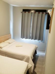 2 camas en una habitación con ventana en Orquidário Praia Hotel, en Santos