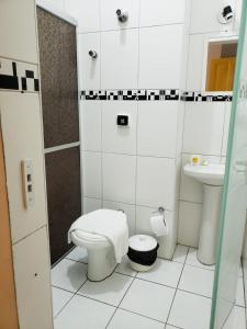 Baño blanco con aseo y lavamanos en Orquidário Praia Hotel, en Santos