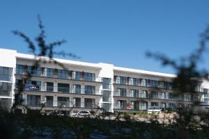 a white building with cars parked in front of it at Apartament Belezza in Dziwnów