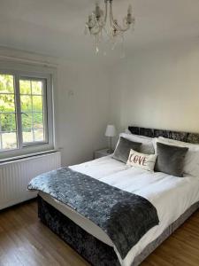 Dormitorio blanco con cama grande y lámpara de araña en Spacious 4-bed Holiday Home in the heart of Maidstone, en Maidstone