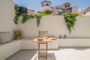 a table on the side of a white wall with plants at ANEMA STYLISH RESIDENCE in Zakynthos Town