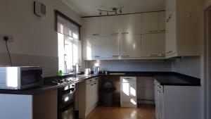 a kitchen with white cabinets and a counter top at Private Rooms just 19 minutes from Central London in Northfleet