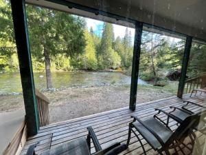 a screened in porch with chairs and a view of a river at Cozy Riverfront Retreat in Leavenworth