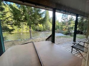a screened porch with a table and a view of a river at Cozy Riverfront Retreat in Leavenworth