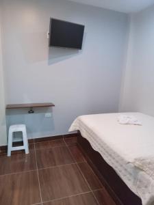 Riojaにあるhospedaje Noemiのベッド1台、テレビ横のスツールが備わる客室です。