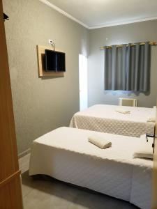 two beds in a room with a tv on the wall at Orquidário Praia Hotel in Santos