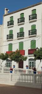 um edifício branco com janelas verdes e uma cerca branca em Casa Pepe La Rosa em Tolox