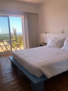 a bedroom with a large bed with a large window at Alto da Lua in Aljezur