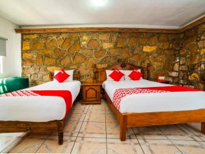 two beds in a room with a stone wall at Casa Banqueta Alta in Guanajuato