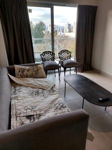 a living room with a couch and a table and a large window at MIRACERROS Departamento en Salta in Salta