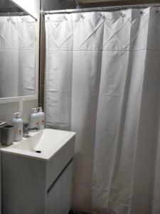 a bathroom with a white shower curtain and a sink at MIRACERROS Departamento en Salta in Salta