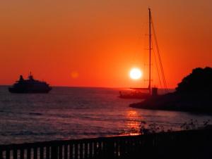 un barco en el océano con una puesta de sol en Apartman Lucy, en Hvar