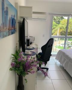 a room with a desk with a chair and flowers at Rio Stay Suite B in Rio de Janeiro