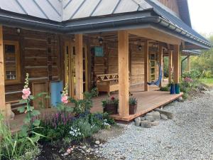 eine Holzhütte mit einer Veranda mit Blumen darauf in der Unterkunft Chyża Hapełe in Zatwarnica