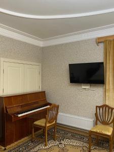 - un piano dans une pièce avec deux chaises et une télévision dans l'établissement Hestia, à Gyumri