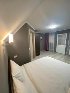 1 dormitorio con 1 cama blanca grande en una habitación en La Izvoare Pensiune-Păstrăvărie, en Sîmbăta de Sus