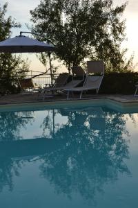 a swimming pool with chairs and an umbrella and some water at Villa Malandrino Guest House in Agropoli