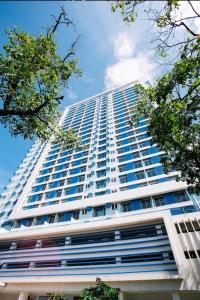 un edificio alto de color blanco con ventanas azules y árboles en Delta Charlie Staycation CDO, en Cagayan de Oro