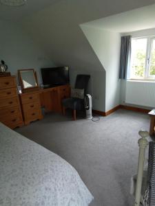a bedroom with a bed and a dresser and a television at White Cottage B and B in Spilsby