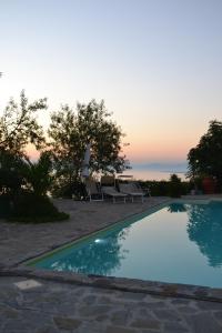 a swimming pool with two chairs and a sunset at Villa Malandrino Guest House in Agropoli