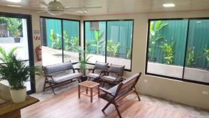 a lobby with chairs and a table and windows at La Posada del Mar in Dominical