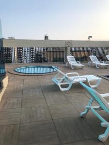 a deck with chairs and a pool on a building at Palladium Apart Service in São Vicente