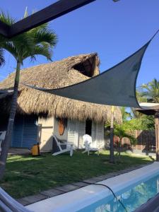 une maison avec un toit de chaume et une piscine dans l'établissement KokohauBungalows, à Santa Veronica