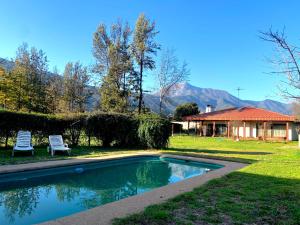 - une piscine avec 2 chaises et une maison dans l'établissement Casa tranquila y central con piscina en Olmué, à Olmué