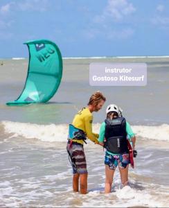 two people standing in the water on the beach at Pousada Casa de João Kitehouse in São Miguel do Gostoso +59 photos