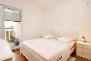 a white bedroom with a bed and a window at Apartment Happy Day in Split