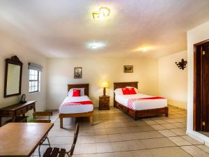 Cette chambre comprend deux lits, une table et un bureau. dans l'établissement Casa Banqueta Alta, à Guanajuato