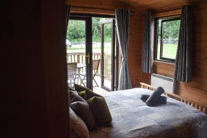 a bedroom with a bed and a balcony with windows at Lodge at Loch Lomond in Glasgow