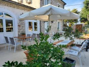 eine Terrasse mit einem Sonnenschirm, Tischen und Stühlen in der Unterkunft Boutique Vila Marijini Dvori in Tribunj