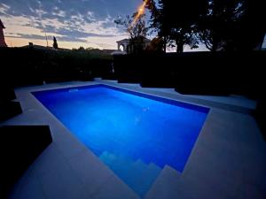 a blue swimming pool in a backyard at dusk at Villa Danza Del Mar - Designed for Adults in Vir