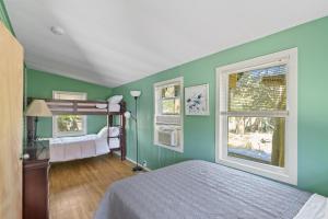 a bedroom with green walls and a bunk bed and two windows at Sea La Vie in Ocean Beach