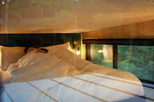 a bed with white sheets and pillows next to a window at Inspire Tiny in Saint-Laurent