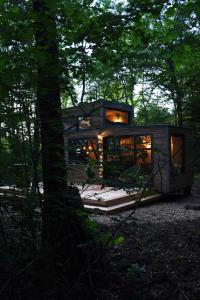 uma pequena casa na floresta com luzes acesas em Inspire Tiny em Saint-Laurent