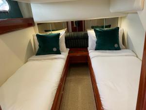 2 camas en una habitación pequeña con almohadas verdes en Tranquility Yachts -a 52ft Motor Yacht with waterfront views over Plymouth. en Plymouth