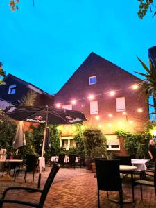 eine Terrasse mit Tischen und Sonnenschirmen vor einem Gebäude in der Unterkunft Hotel Altes Gasthaus Düsterbeck in Emsdetten