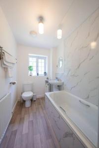 a white bathroom with a tub and a toilet at Stylish 2-bed home - For Company contractor and Leisure stays - NEC, Airport, HS2, Contractors, Resort World in Birmingham