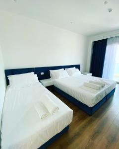 two beds in a room with white walls and wood floors at SEA & LAKE VIEW VILLA in (( Kalive Gjoka ))
