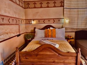 un letto con testiera in legno in una stanza di Hôtel panoramique de la vallée ad Aït Idaïr