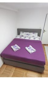a purple bed with two pairs of slippers on it at Apartman Kristina in Trebinje