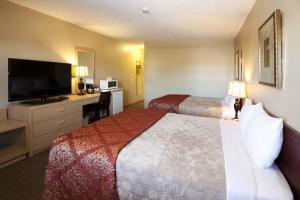 a hotel room with two beds and a flat screen tv at Bow River Inn in Cochrane