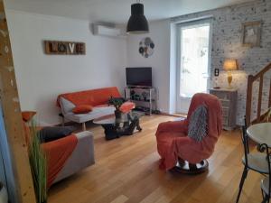 un salon avec un canapé, des chaises et une télévision dans l'établissement Maison de village avec cour intérieure et terrasse, à Septfonds