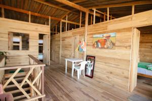 Habitación de madera con mesa y cama en Puerto Manglar Hostel, en Guachaca