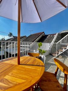 une table en bois avec un parasol sur une terrasse dans l'établissement ElBanna FAmily Home syariah 5BR, à Malang